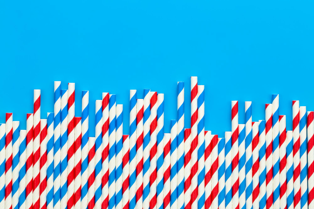 A collection of unique wrapped red, white, and blue straws arranged on a vibrant blue background.