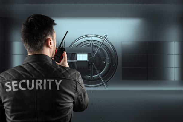 A man in a black jacket gazes at a bank vault, illustrating the significance of security from Salum Security Guard Patrol Services.